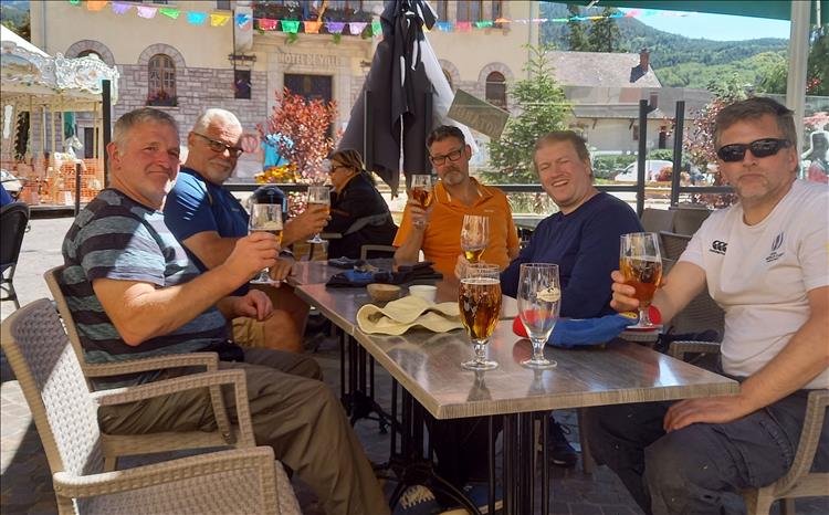 The friends sitting around a table in the sun under a shade in the town centre
