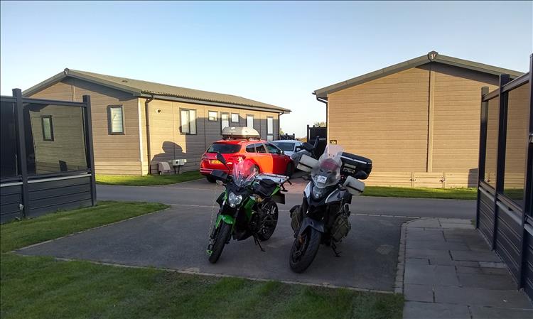 Sharon and Ren's bikes on a section of tarmac specifically for parking with other lodges behind