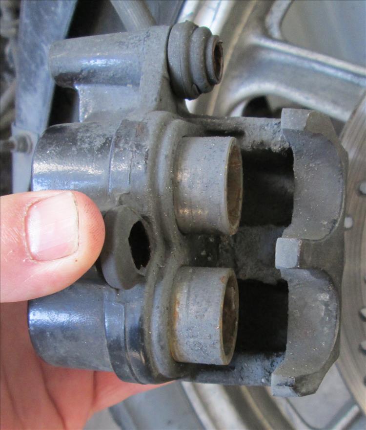 Very dirty pistons most of the way out on a motorcycle's calliper