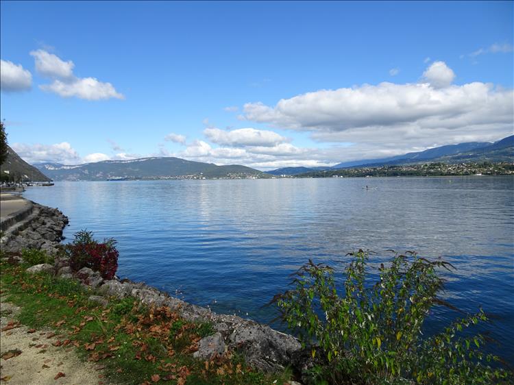 Calm flat lake, hills in the distance, clear skies with the odd fluffly clouds and a lovely scene
