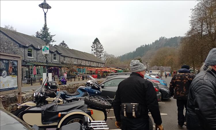 A few bikes and riders at Betws-Y-Coed with stone shops and parade