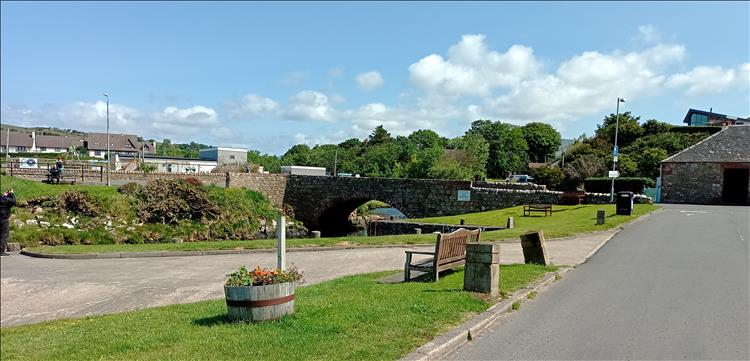 A bench, the mouth of a small river, a bridge and a few houses on the Isle of Arran