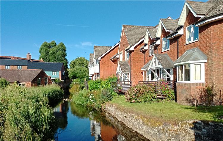 A small brook runs by modern houses in a pretty scene