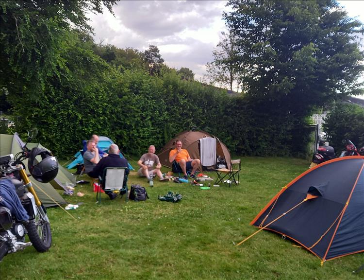 The lads sitting around with the tents and bikes at the campsite