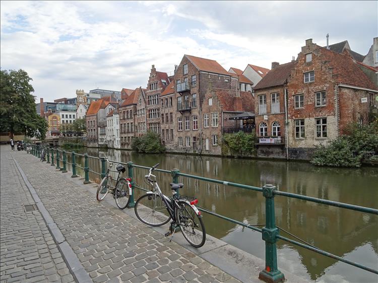 A canal runs beside the road and tall houses, a few bicycles here and there