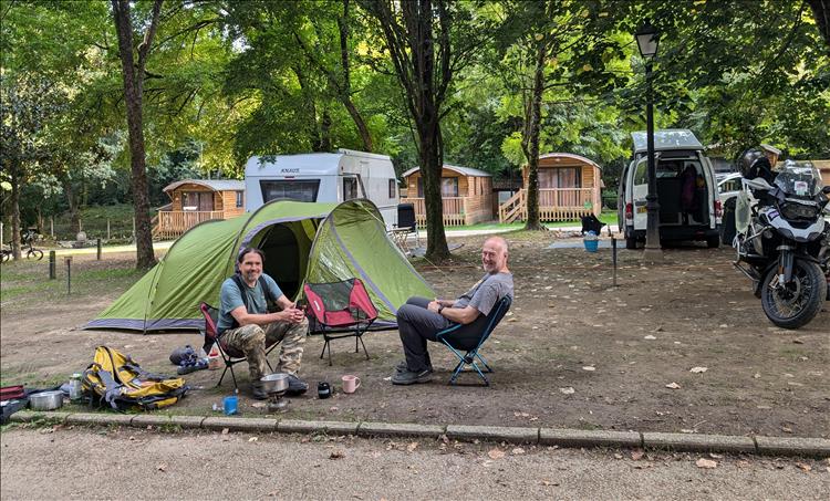 Ren and Andy sit on their camping chair under the trees at the campsite in Northern Spain
