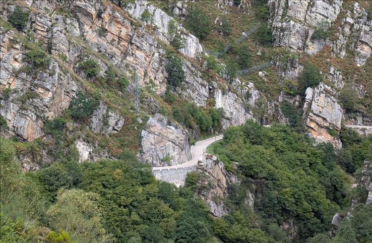 The road clings to the almost vertical rocks and is narrow with low concrete barriers