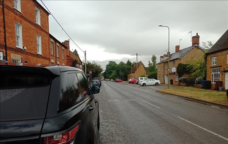 A pleasant main street in a typical English village, but the skies are heavy and dark