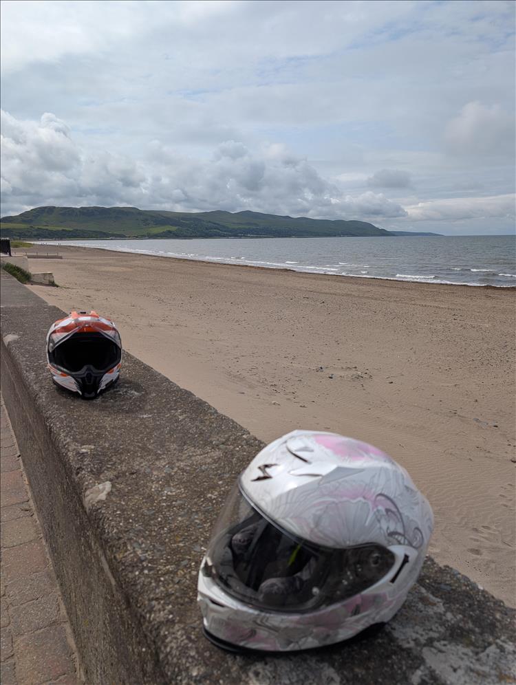 2 helmets on a low sea wall with the beach and hills in the background at Girvan