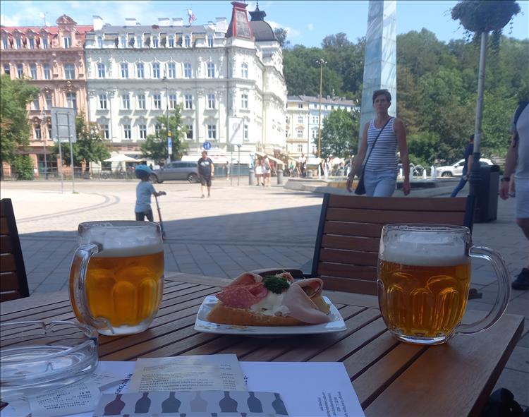 Beer and open sandwiches on a table with the period buildings as the backdrop
