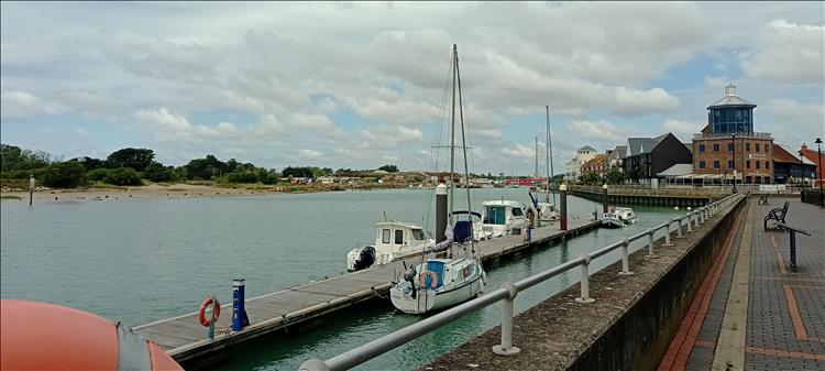 The river Arun runs through the town of littlehampton with small boats moored and apartments beside the river