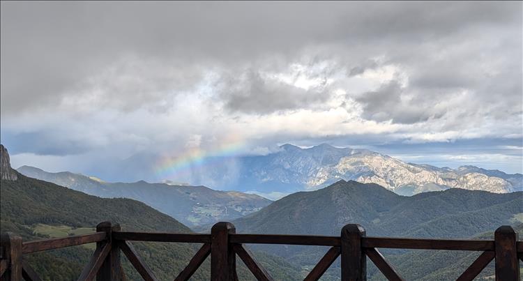 Heavy skies and a rainbow over vast impressive mountains