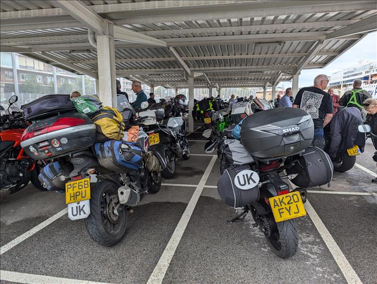 A vast array of motorcycles and riders all waiting under a steel canopy at the port