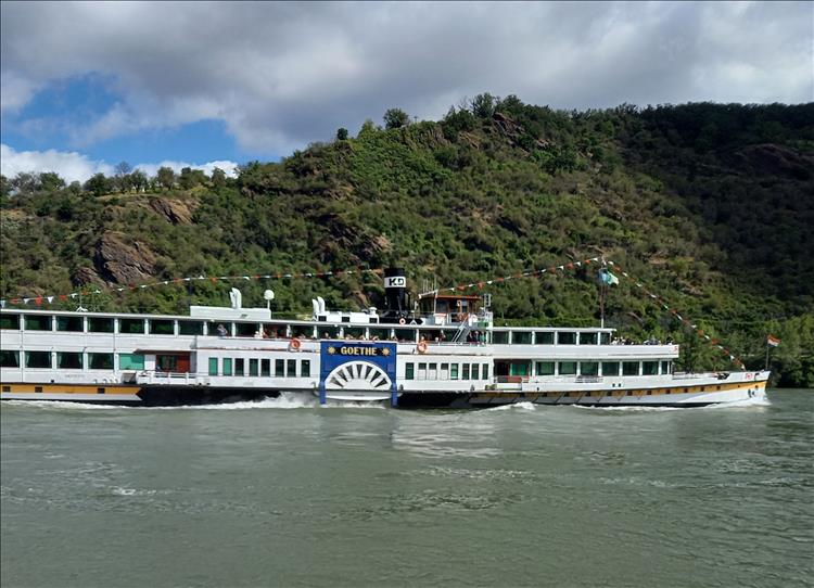 A long low river cruise boat with paddles on the river