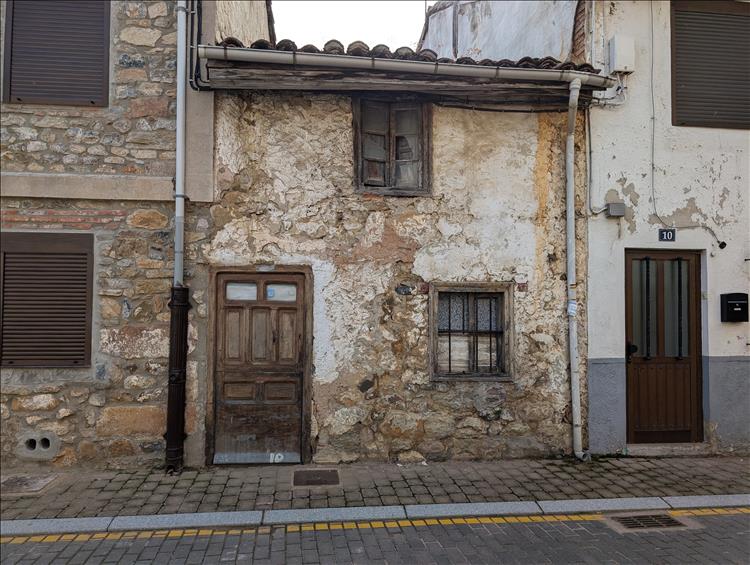 Between taller new houses is a tiny ramshackle old house