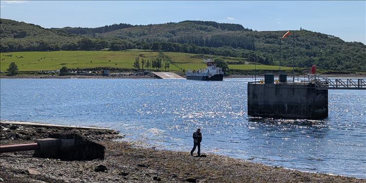 Clear skies, a narrow loch, a rider beside the shoreline and the ferry to bute