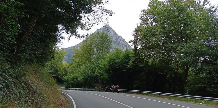 A sharp high rocky peak seen from the road and trees on the Spanish N629