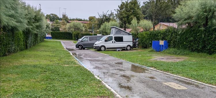 2 campervans, soggy grass, puddles on the road and leaden skies at the campsite in Santander