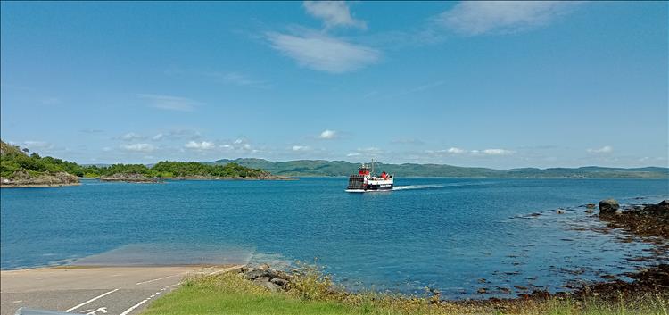 A mid sized ferry coming to a concrete ramp set amidst the wonderful highland scenery