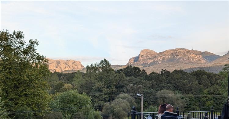 Beyond a few trees and the balcony of the bar there's the rocky tops of nearby mountains