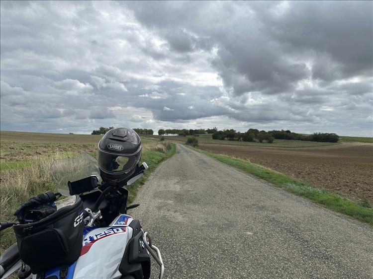 A narrow lane winding away through fields and hills under heavy skies