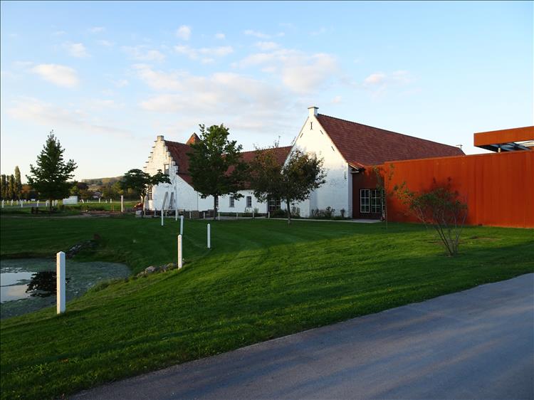 The white painted hotel is set by grass and hills and trees