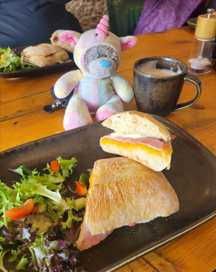 The stuffed toy cute unicorn on the table as we eat our sandwiches