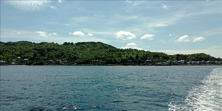 From the ferry we see the calm waters and the tree covered hills