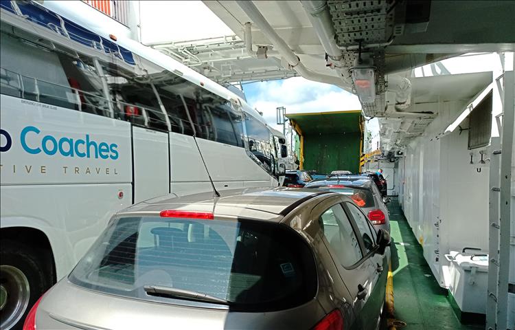Within the ferry on the vehicle deck. It's packed with a coach, many cars and passengers