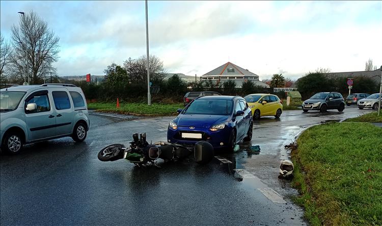 The Z400 lies on it's side in the road with a car behind