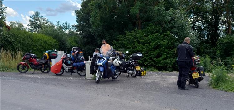 The motley collection of small scooters and motorcycles parked in a layby