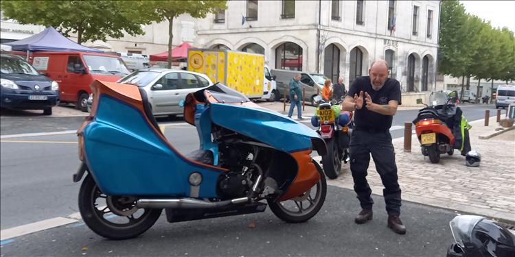 A home made feet forwards motorcycle, a chap moving his arms expressively in a french town