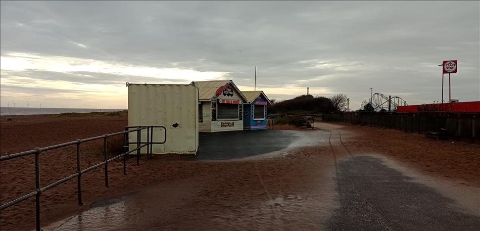 Dark skies, an empty beach save for the shuttered tea and ice cream cabins, a roller coaster in the distance