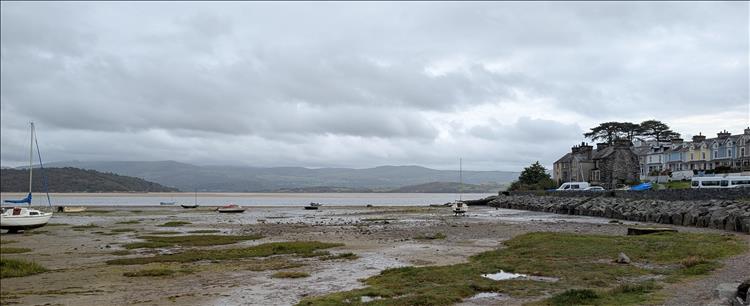 With the tide out there's boars on the sand at the harbour, the sea is out there and hills beyond