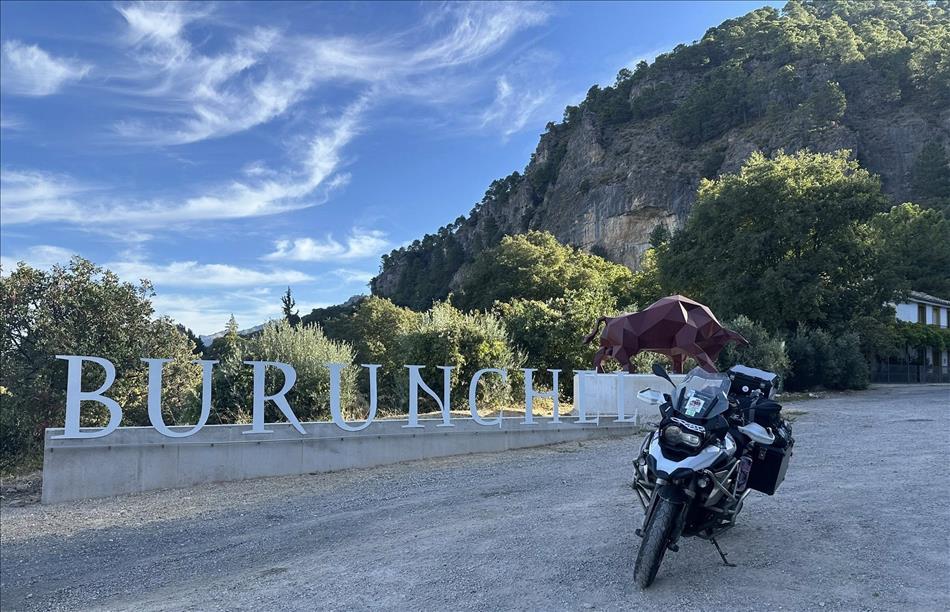A large long sign and stylised bull beside a gravel layby and mountain
