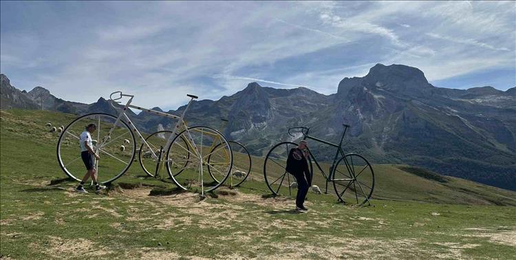 Large metal statue pedal cycles on a mountainside field