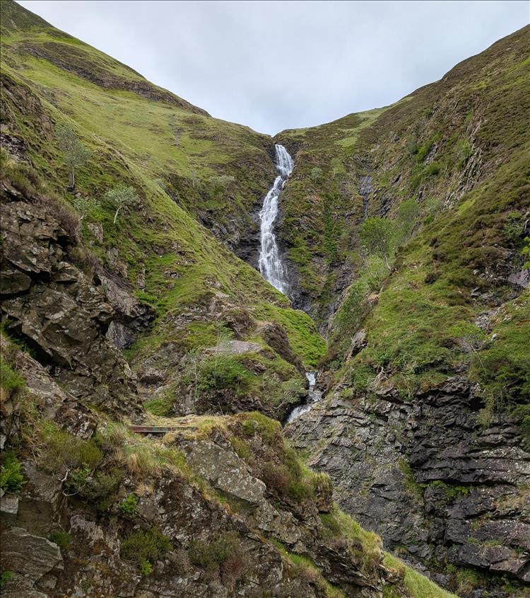 Steep almost V shape through the hillside with a narrow steep waterfall between the rocks