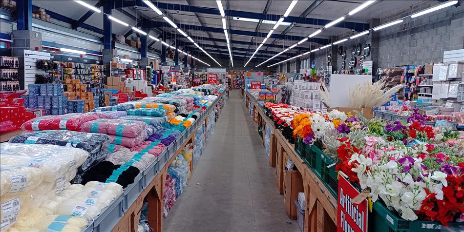 Long long benches filled with all kinds of things to buy like wool or artificial flowers or tools