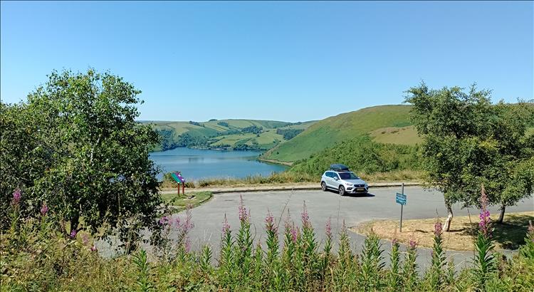 A car in an otherwise empty car park with the wonderful Welsh scenery all around