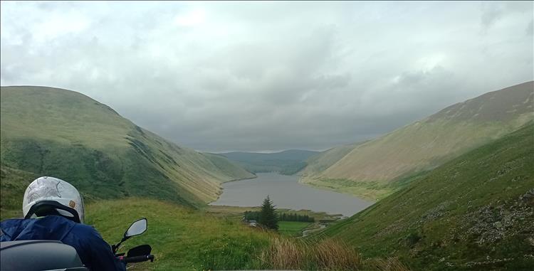 From a high road we look down into the valley and the reservoir between huge fat mountains