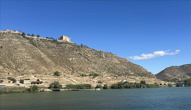 Atop a steep dry slop we see the remnants of a castle baking in the sun