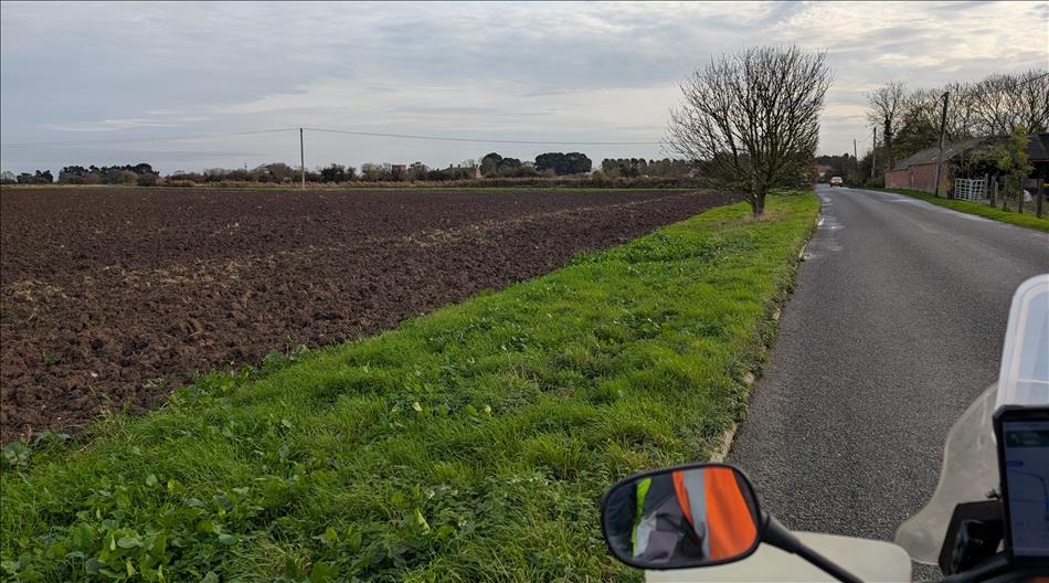 Seen from the bike's seat the road has only the gentlest of curves besides flat fields and the distant trees or houses