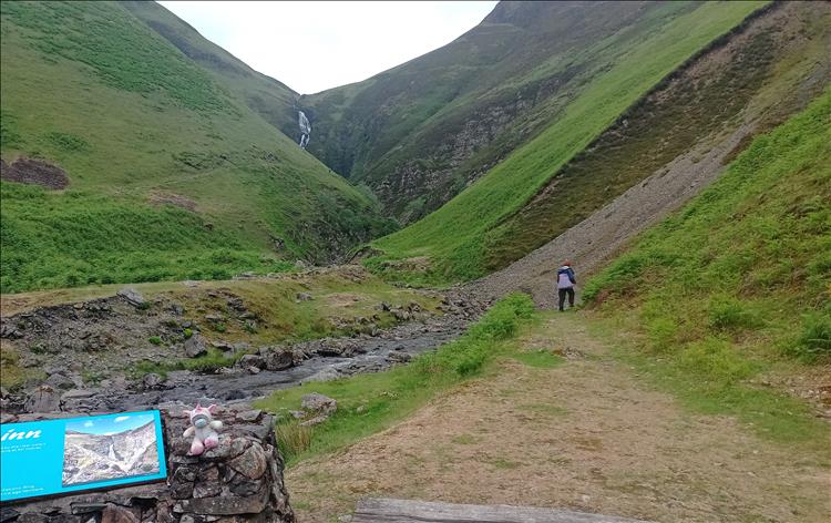 A narrow waterfall between big steep valley sides, Sharon wandering off towards it all