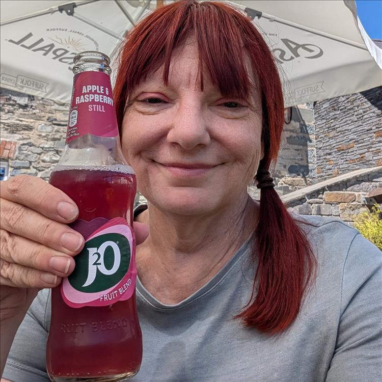 Sharon smile while holding up a bottle of J2O