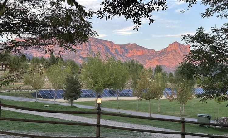 As the sun sets the side of a rocky mountain is illuminated in a stone orange