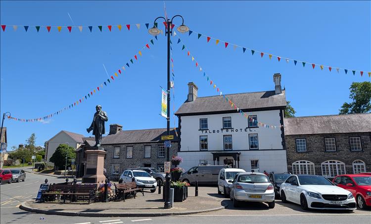 A white painted pub, a statue, bunting and blue skies in Tregaron