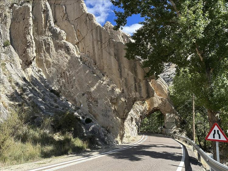 Rocks form an arch over the narrow lane, steep and jagged