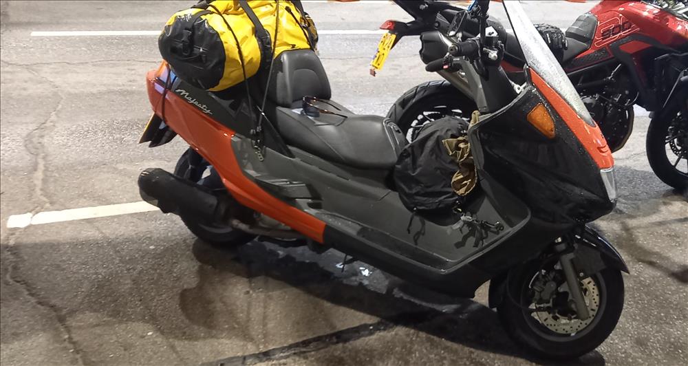 An orange Yamaha scooter with luggage filling the back seat
