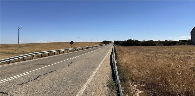 A lonely road, the gentlest of undulations on an otherwise flat scene of dry grasses