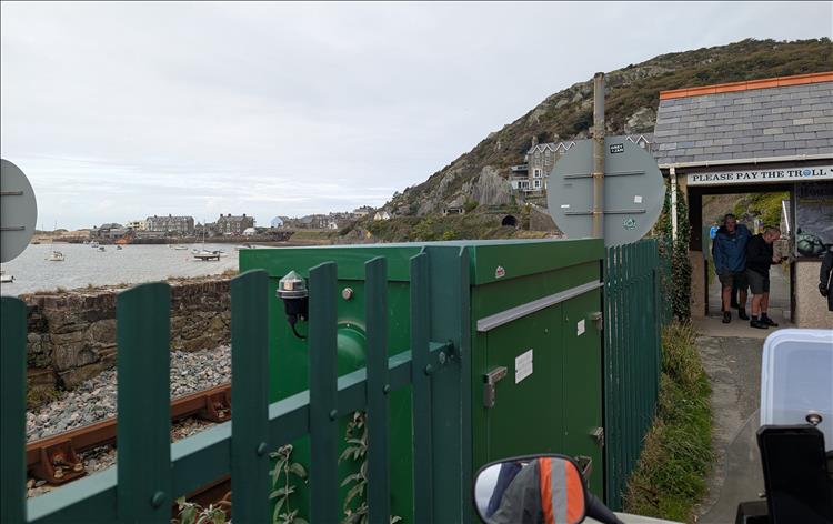 A small brick built toll booth with pedestrians at the Barmouth end of the bridge